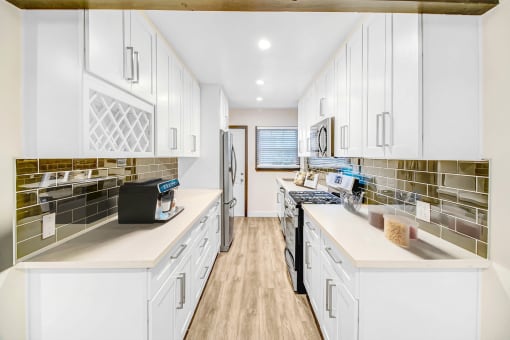 a large kitchen with white cabinets and stainless steel appliances
