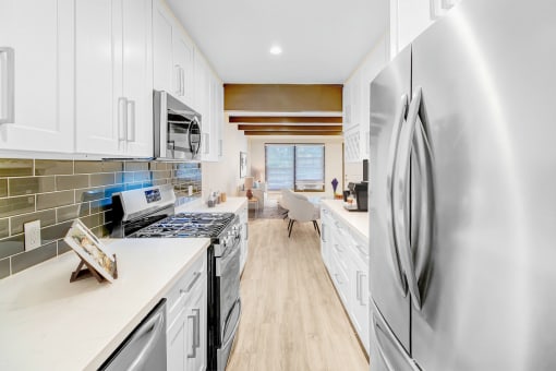 a white kitchen with stainless steel appliances and white cabinets