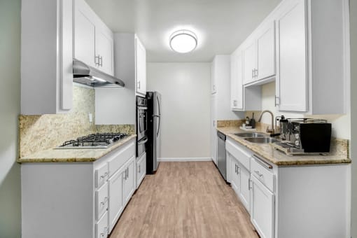 an empty kitchen with white cabinets and a counter top