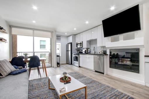 Furnished 1 Bedroom Suite, living room with cozy fireplace, dining area on the left with private balcony, open kitchen