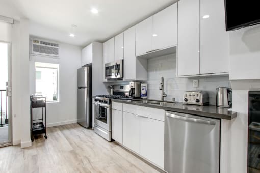 Furnished Kitchen with stainless steel appliances, black quartz countertops