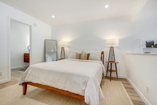 Sleeping area with recessed lights, plank flooring, bathroom on the left
