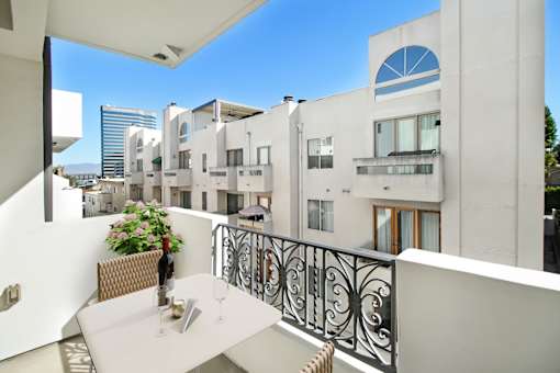 a balcony with a table and chairs and a building in the background