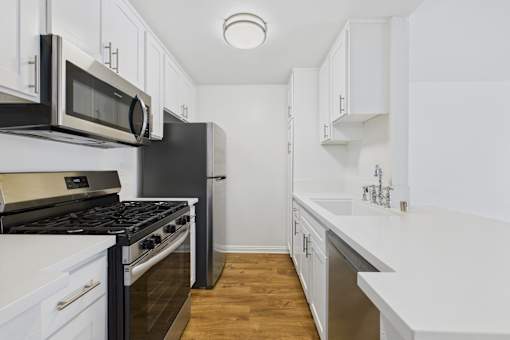 A kitchen with black and white appliances and wooden floors.