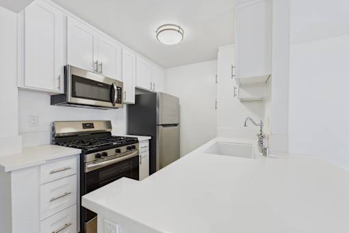 A kitchen with white cabinets and appliances.