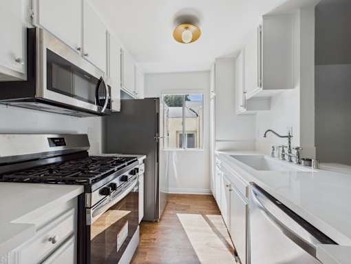 A modern kitchen with white cabinets and black appliances.