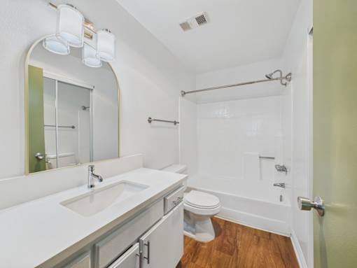 A white bathroom with a toilet, sink, and mirror.