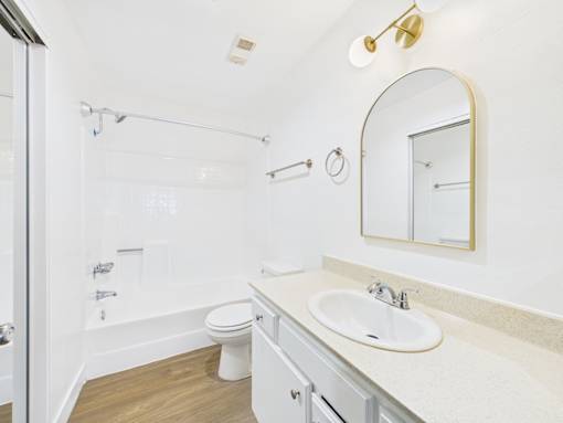 A white bathroom with a sink, mirror, and toilet.