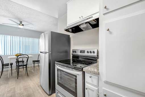 A kitchen with a refrigerator, oven, and stove.