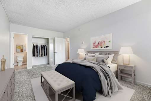 A bedroom with a bed, nightstand, and a bench.