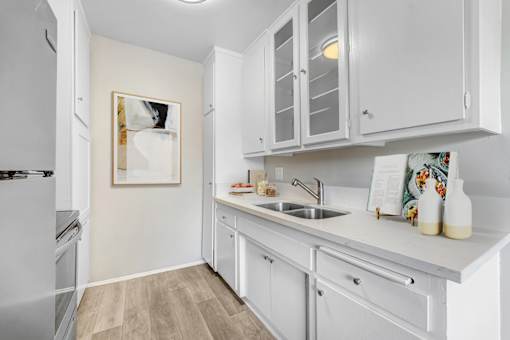 A kitchen with white cabinets and a fridge.