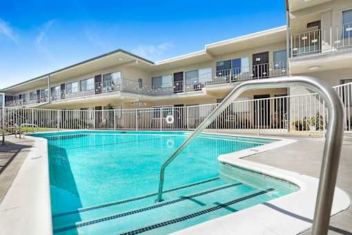 A swimming pool in front of a building with a metal railing.