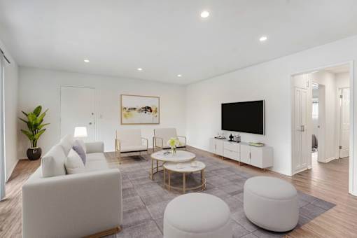 A modern living room with a white sofa, a coffee table, and a TV.