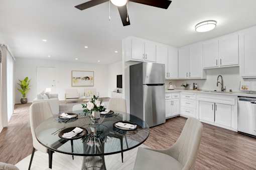 A modern kitchen with a glass dining table set for four.