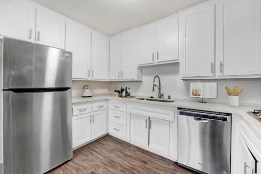 A kitchen with white cabinets and a stainless steel refrigerator.
