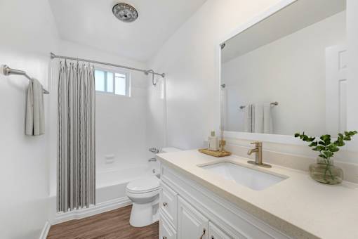 A white bathroom with a toilet, sink, and shower.