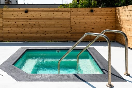 a hot tub with a wooden wall and a stainless steel hand rail