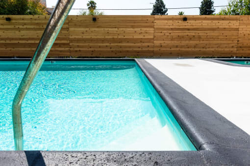 a swimming pool with a concrete coping and a wooden fence