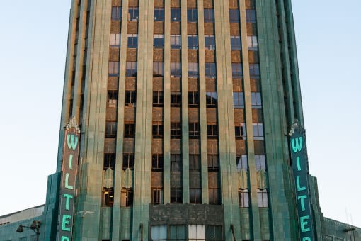a tall brown and green building with a blue sky in the background
