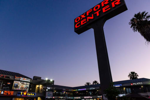 a large illuminated sign in front of a shopping center at night