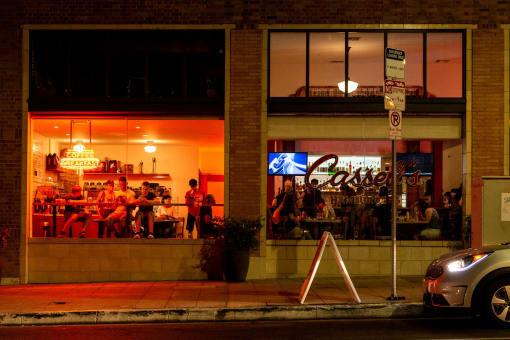 a restaurant with people sitting in the windows at night