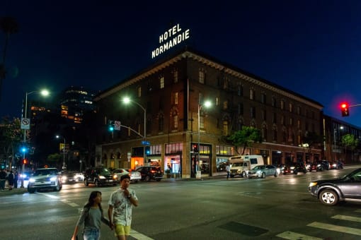 a couple crossing the street in front of a hotel at night