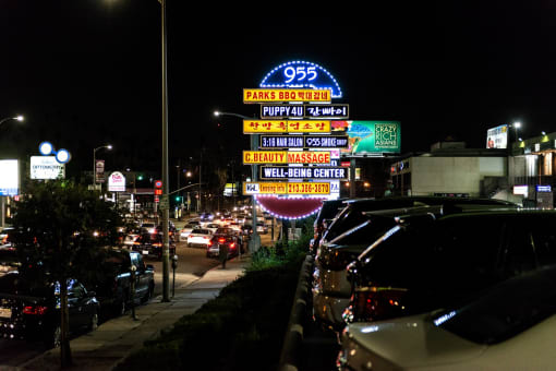 a busy street at night with cars parked on the side of the road