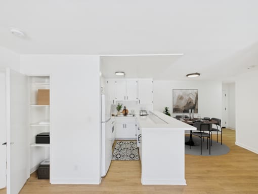 A kitchen with white cabinets and a dining table with chairs.