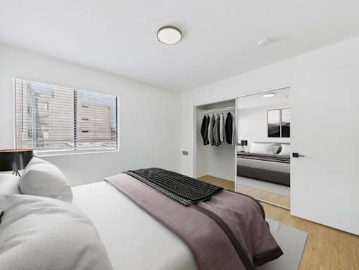 A bedroom with a bed, a mirror, and a wardrobe.