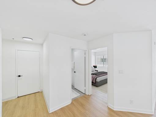 A white bedroom with a round light fixture on the ceiling.