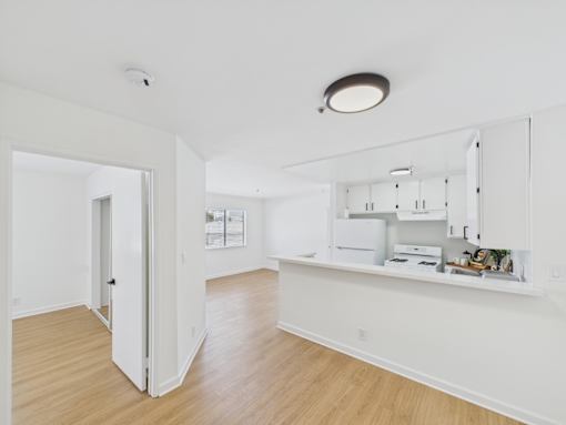 A white kitchen with a white fridge and cupboards.