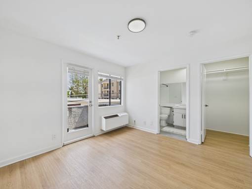 A white room with a window and a door leading to a bathroom.