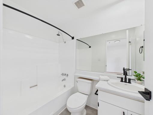 A white bathroom with a toilet, sink, and shower.