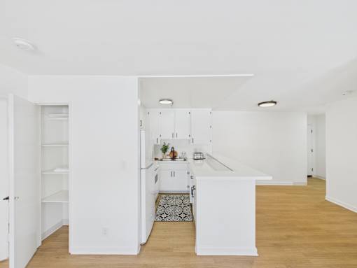 A kitchen with white cabinets and a white island.