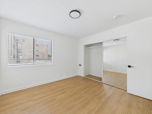 A room with a white wall and a window with blinds.