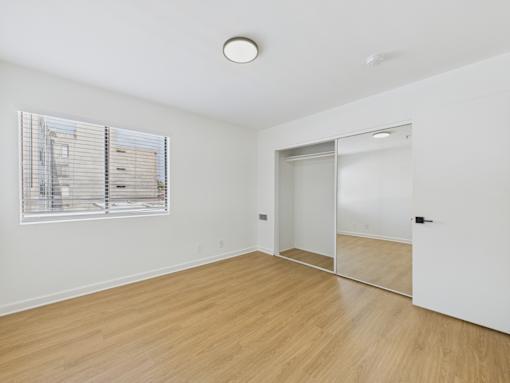 A room with a wooden floor and a window with blinds.