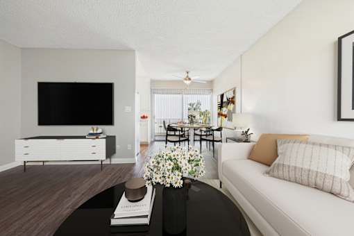 A living room with a white couch, a black coffee table, and a flat screen TV.