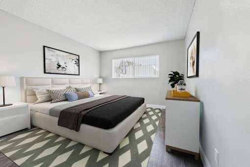 A bedroom with a large bed and a nightstand with a plant on it.