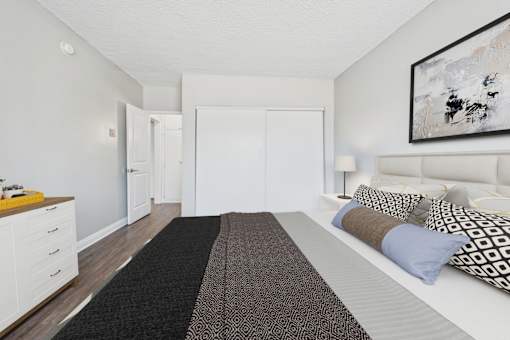 A bedroom with a bed, dresser, and a painting on the wall.