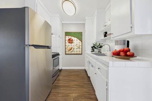 A kitchen with a black refrigerator and white cabinets.