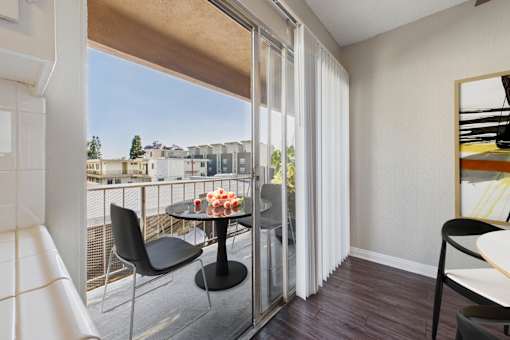 A balcony with a table and chairs overlooking a cityscape.
