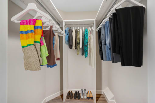 a walk in closet with a white closet organizer