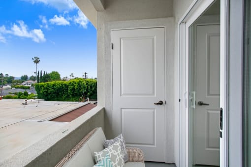 a balcony with a white door and a white couch with pillows