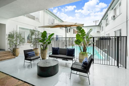 a patio with chairs and a table and a pool in the background