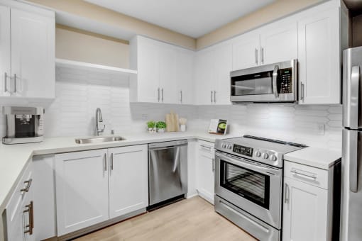 a white kitchen with stainless steel appliances and white cabinets
