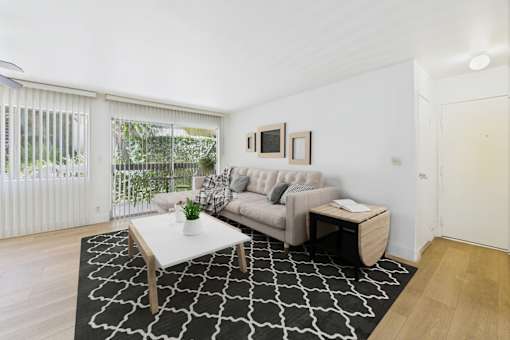 A living room with a couch, coffee table, and a rug.