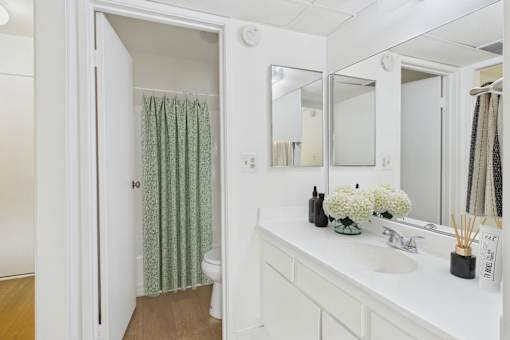 A white bathroom with a toilet, sink, and mirror.