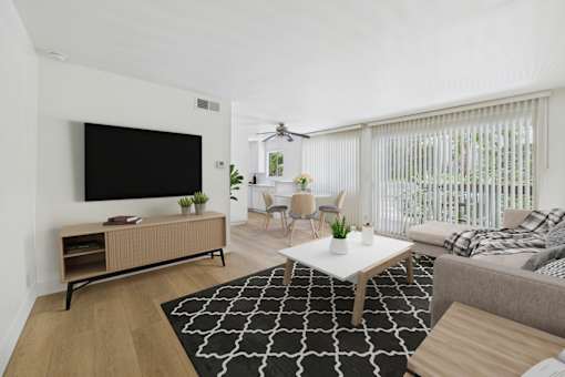 A living room with a black and white rug, a white coffee table, a grey couch, a wooden cabinet, a flat screen TV, and a ceiling fan.