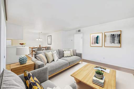 A living room with a grey couch, a wooden coffee table, and two framed artworks on the wall.