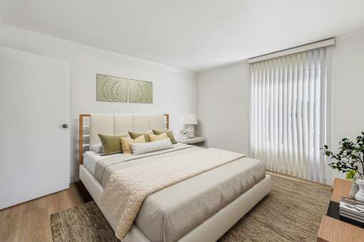 A bedroom with a large bed and a window with curtains.